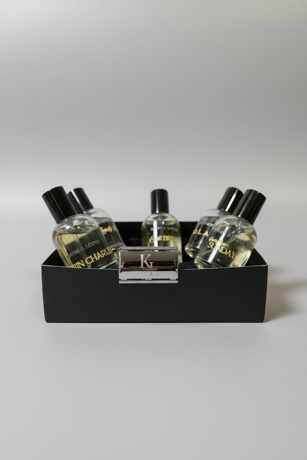 A boxed set of Kings & Lotus fragrance products, including several clear glass bottles with black caps and a metallic rectangular razor or accessory in the front