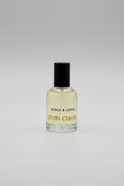 A bottle of Kevin Charles Kings & Lotus cologne with a black cap and gold lettering, resting on a black velvet surface with its black packaging box in the background.