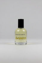 A bottle of Kings & Lotus Cali Breeze fragrance with a black cap, resting on a black fabric surface