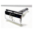 A polished chrome safety razor with a custom-engraved 'K L GROOMING' logo on the front, displayed on a clean white surface.